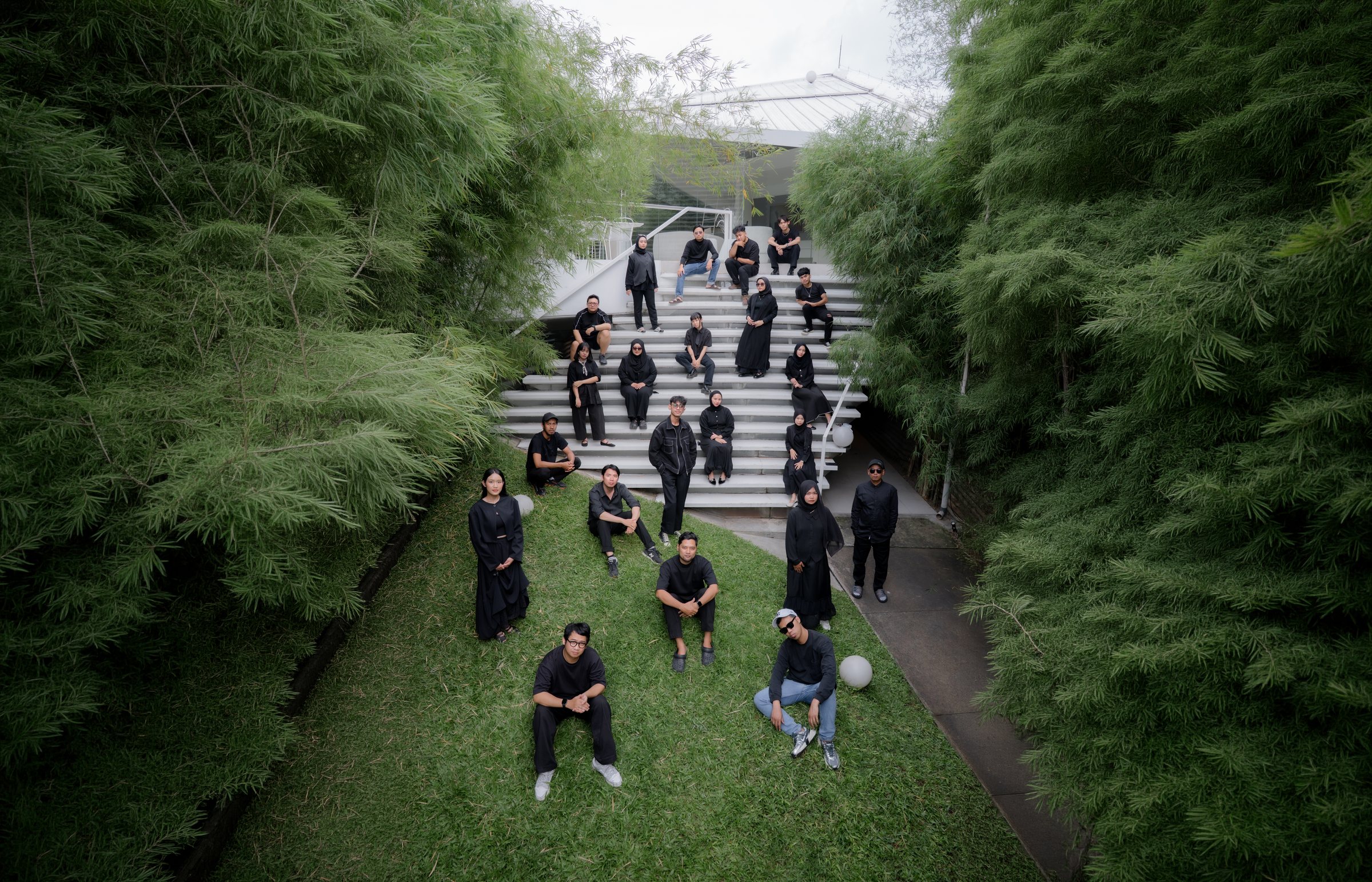 The Kunkun Visual team on the steps of the Bandung studio, between the bamboo